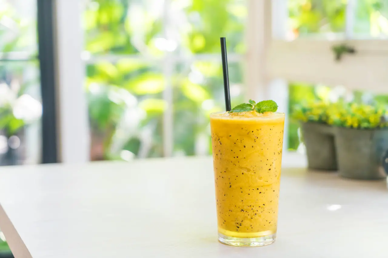 Deliciosa bebida refrescante de manga com maracujá, com textura cremosa e folhas de hortelã, ideal para dias quentes e momentos relaxantes.