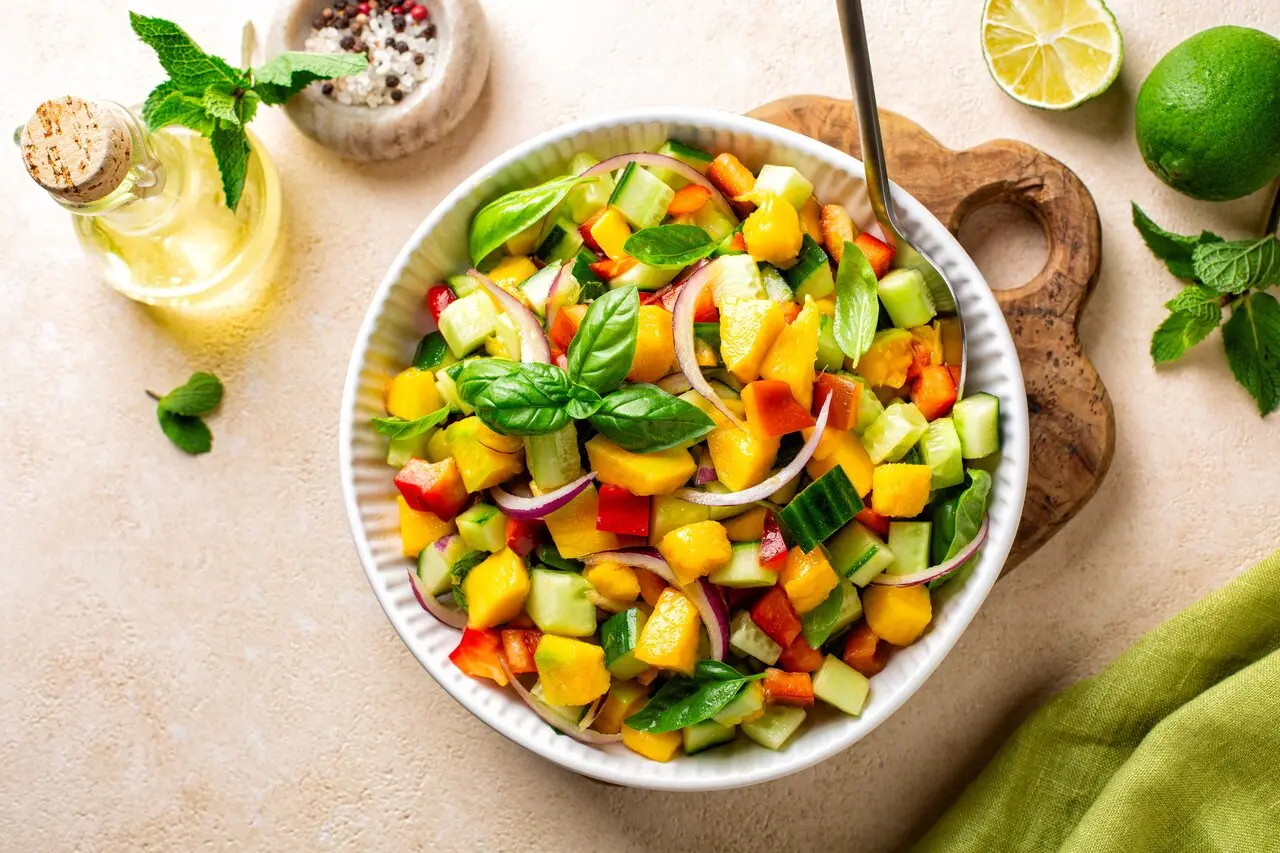 Deliciosa salada colorida com abacate, pimentão, cebola roxa, pepino folhas de manjericão, manga e queijo, perfeita para refeições saudáveis e frescas.