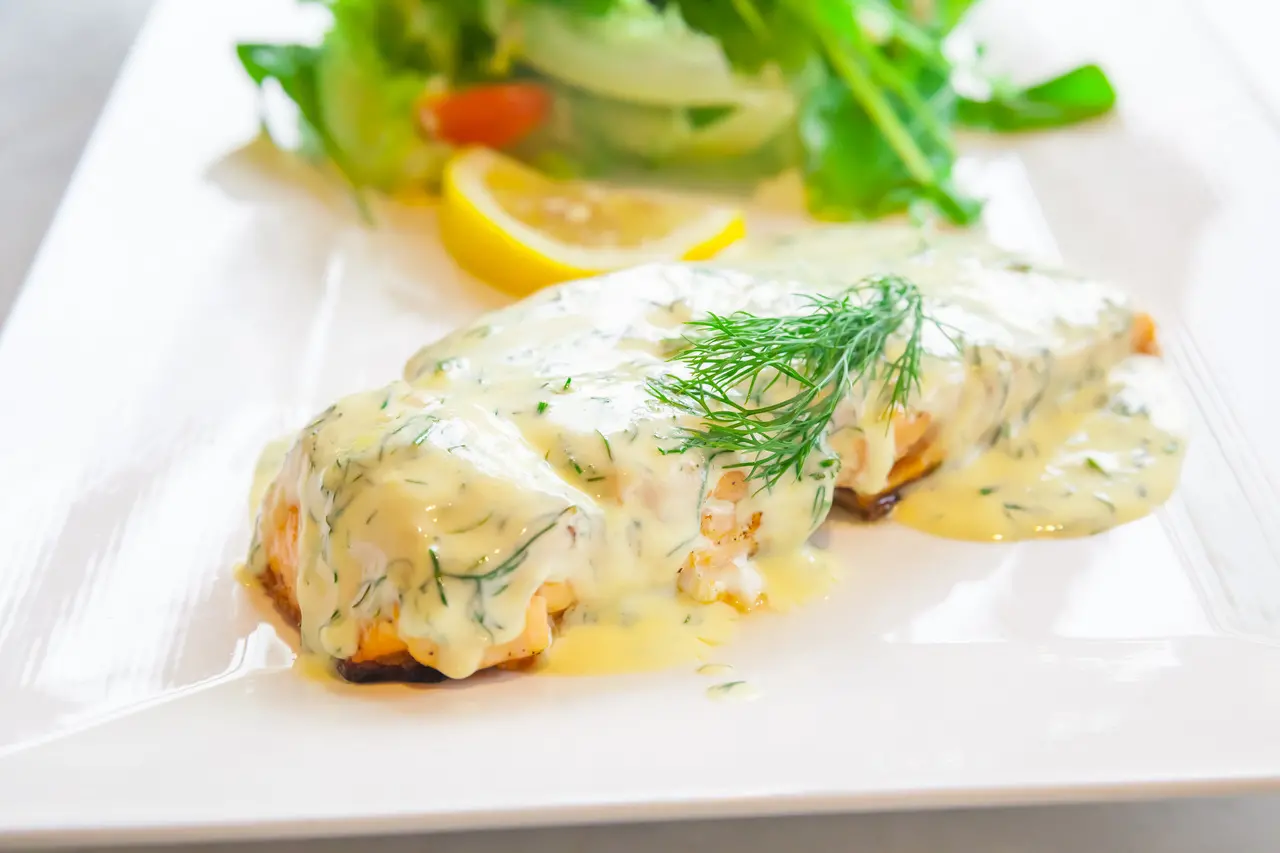 Foto da receita com um filé de peixe e molho branco