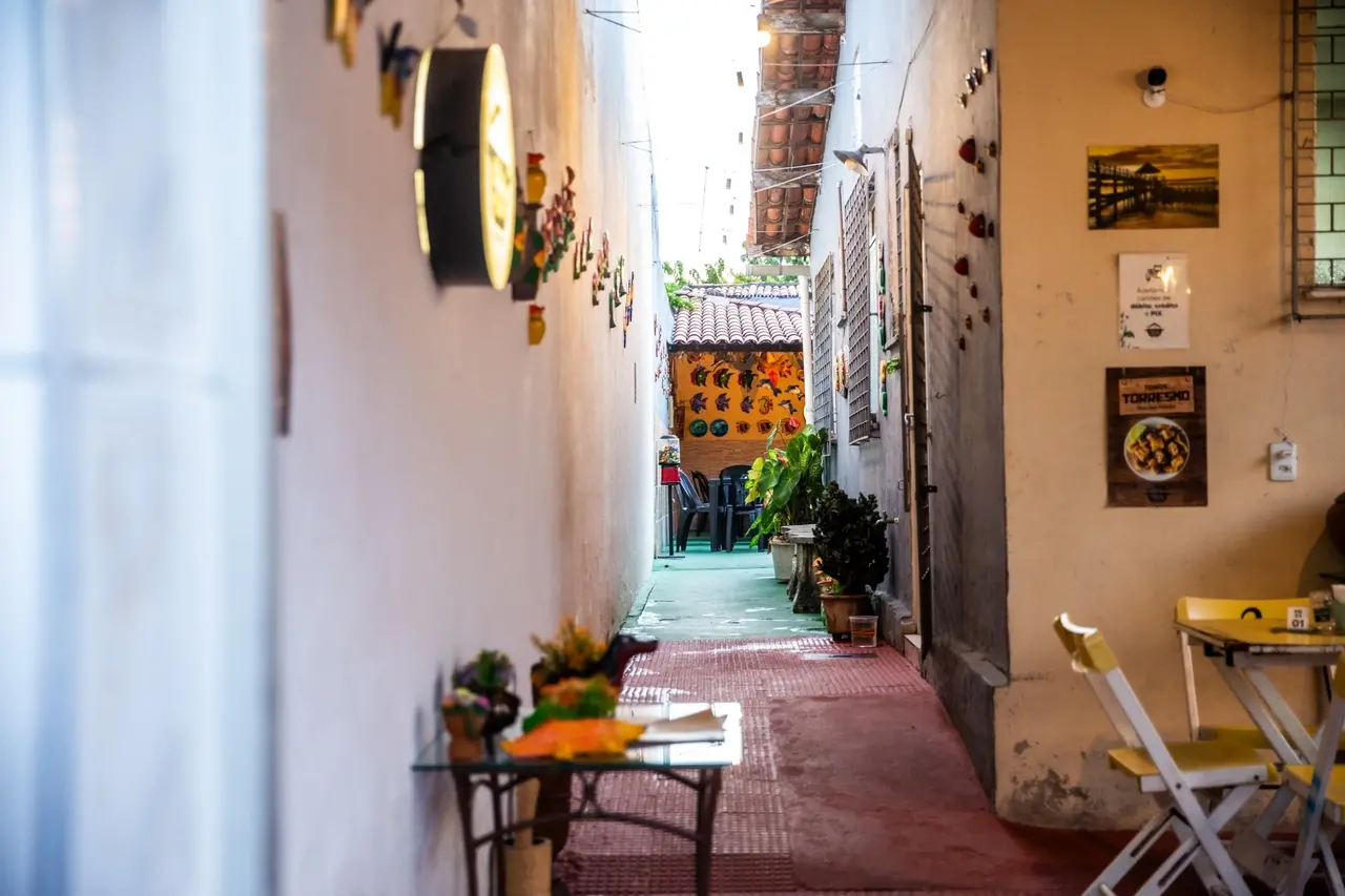 Imagem de corredor que leva ao restaurante Nos Fundos da Clau, em Fortaleza, montado nos fundos da casa do casal proprietário