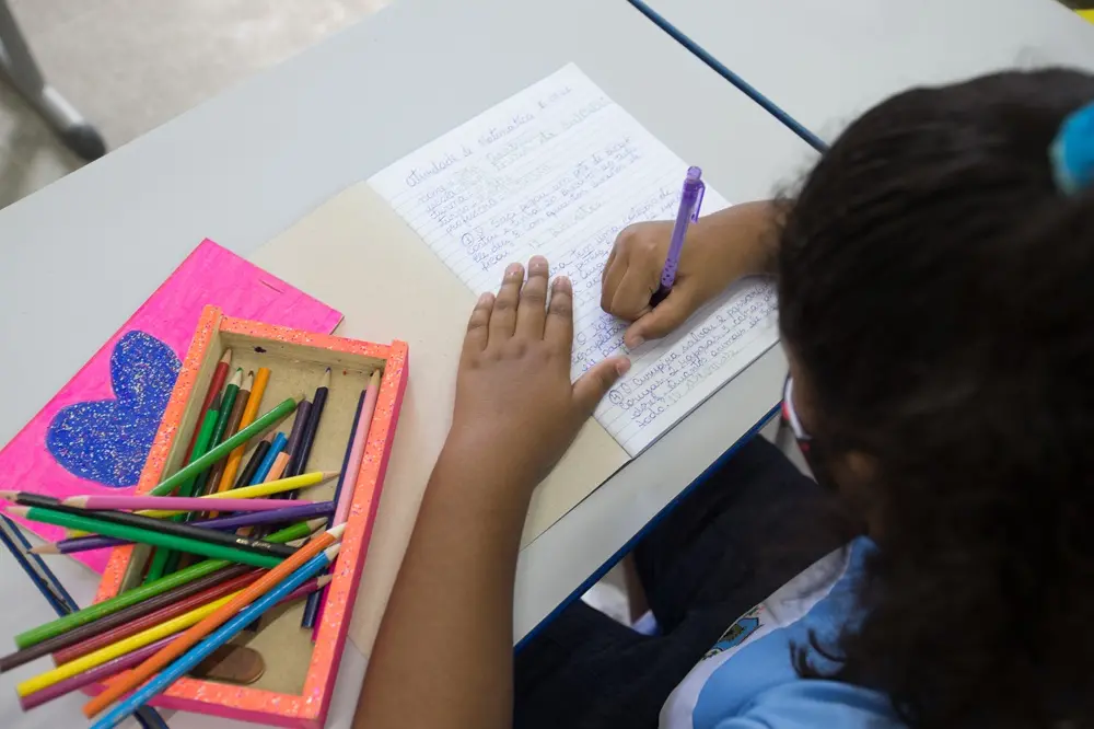 criança escrevendo em sala de aula