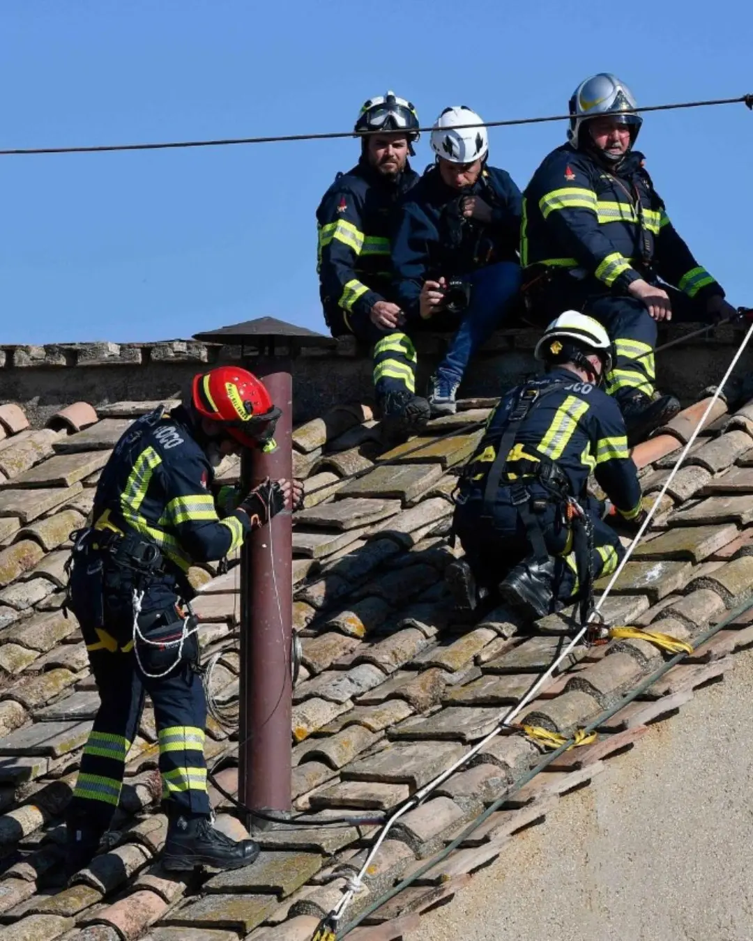Na imagem, bombeiros do Vaticano no topo do telhado da Capela Sistina instalando a chaminé
