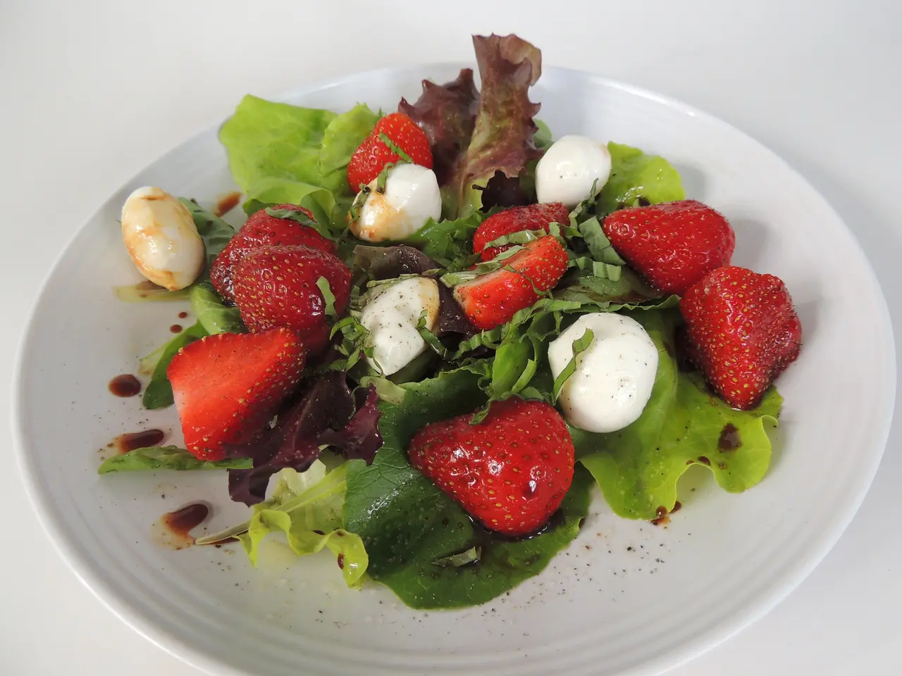 Imagem mostra prato com salada de morango, feita de alface, morangos e muçarela de búfalo, ilustrando receita do prato