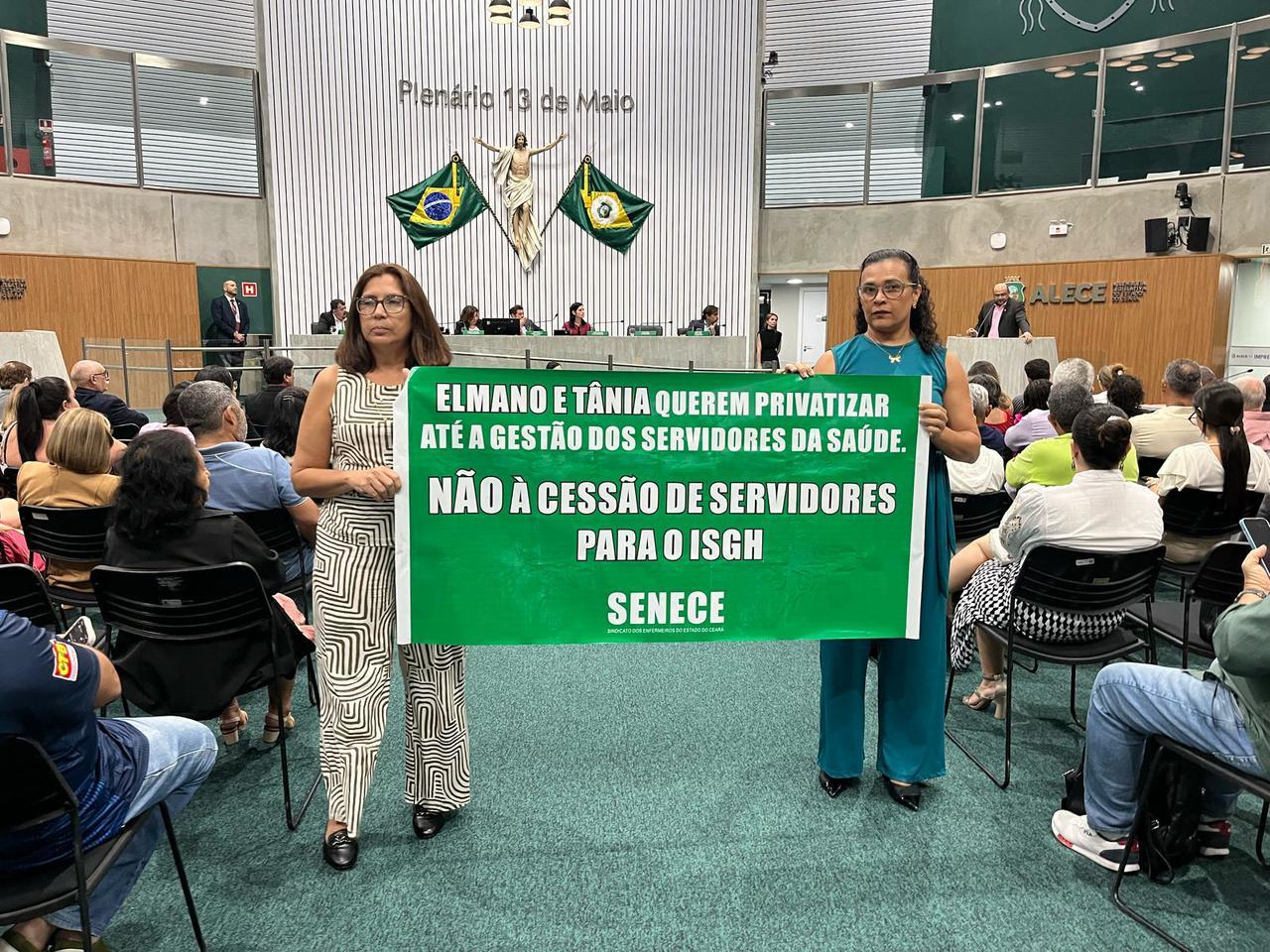 Duas representantes do Sindicato seguram faixa em que está escrito: 