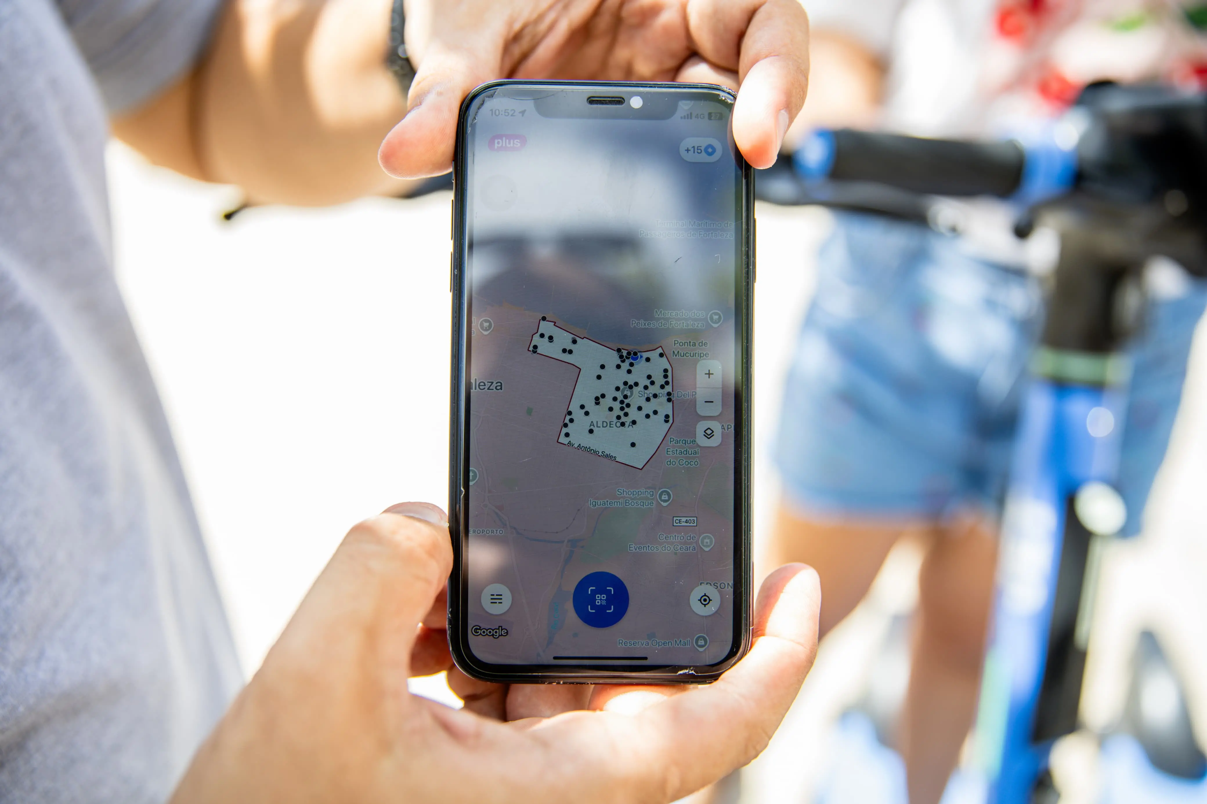 Pessoa usando um smartphone com aplicativo de mapeamento ou navegação, destacando a tecnologia de GPS ou geolocalização ao descansar em uma rua ou área pública.