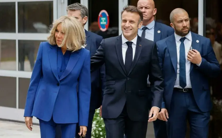 Brigitte Macron e Emmanuel Macron andando pelas ruas com seguranças no seu entorno
