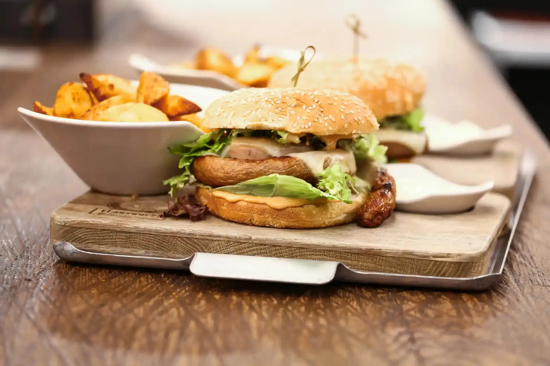 Imagem de um hambúrguer feito com linguiça com batatas fritas ao lado.