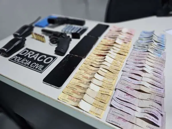 Imagem mostra material apreendido em operação policial: armas, radiocomunicadores e dinheiro
