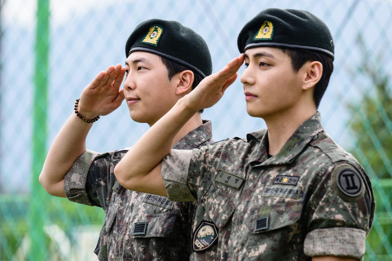 Imagem mostra RM e V usando uniforme do Exército cumprimentando jornalistas e fãs ao ser dispensados, em 10 de junho, na Coreia do Sul