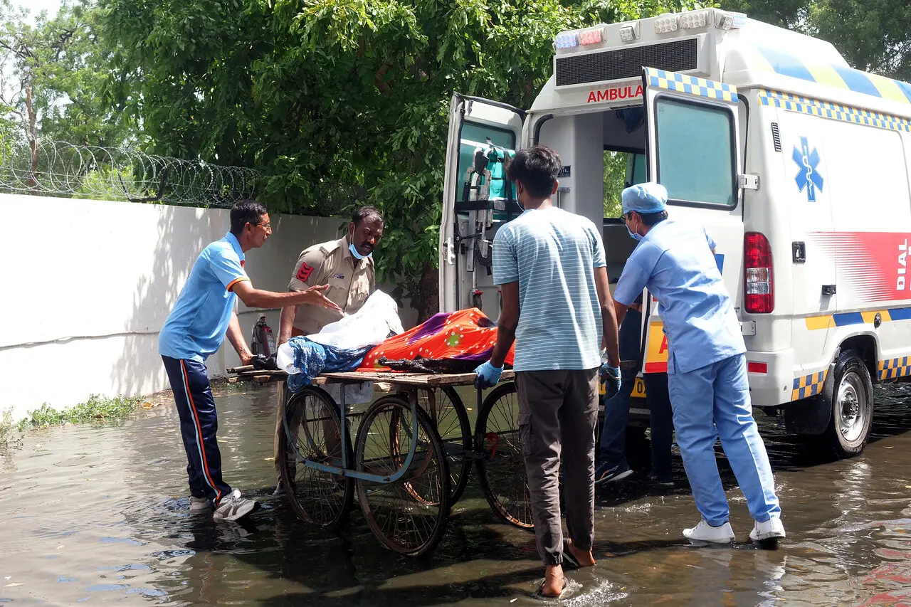 Imagem mostra um policial e paramédicos transferindo os corpos das vítimas para uma ambulância após o voo 171 da Air India ter caído em uma área residencial em Ahmedabad