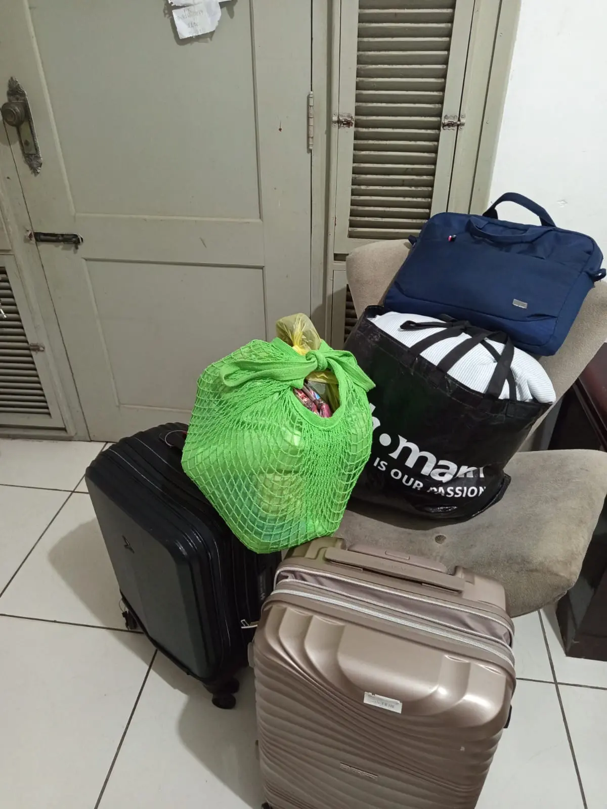 Foto de cinco bolsas que seriam entregues para uma cliente da Uber, em uma corrida na modalidade Uber Flash, em Fortaleza. Há duas malas (preta e bege), uma bolsa preta, uma sacola verde e uma bolsa azul, em cima de uma cadeira