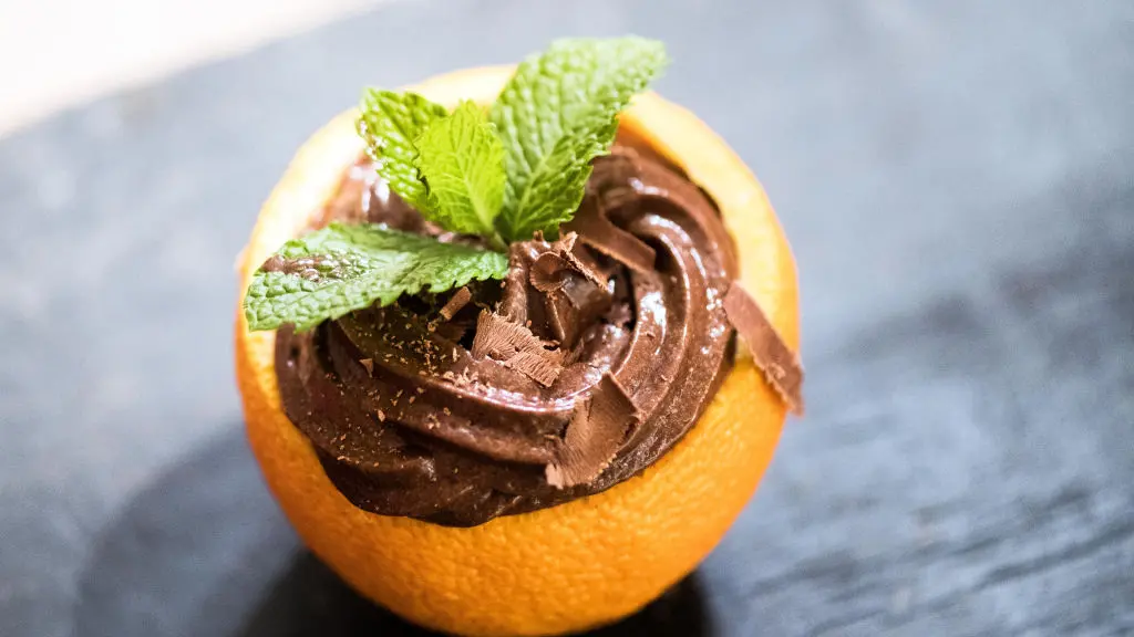 Imagem de uma laranja recheada com creme de chocolate, decorada com folhas de hortelã, ideal para sobremesas saborosas.