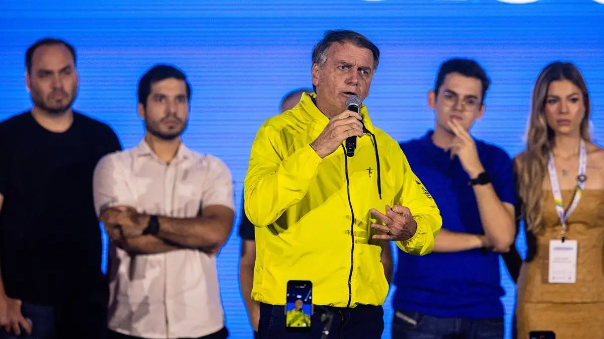 Jair Bolsonaro de jaqueta amarela em palanque de evento no Ceará, ao fundo, seu filho Carlos Bolsonaro, André Fernandes, Carmelo Neto e Bella Carmelo