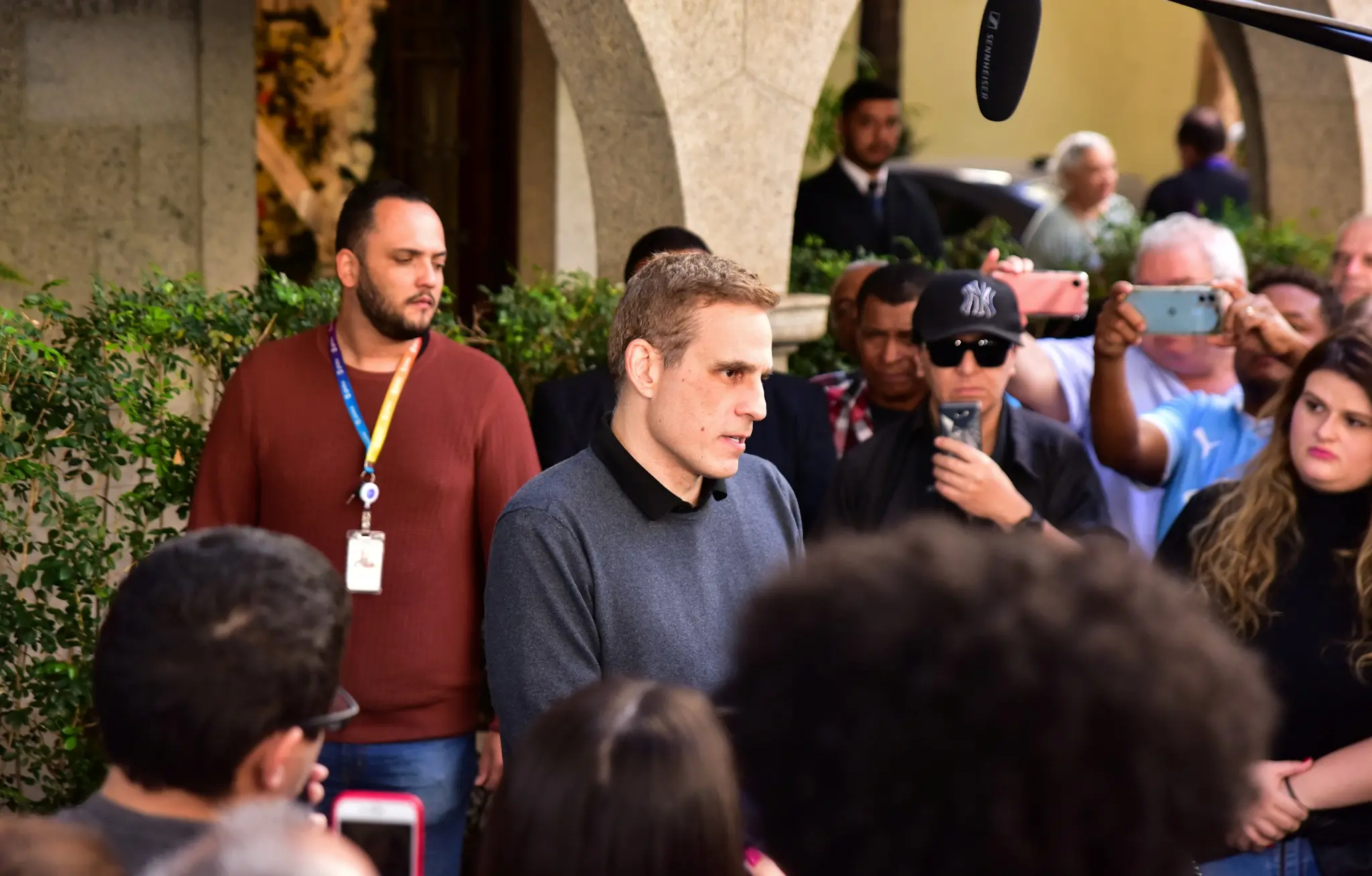 Diogo Cuoco é o centro das atenções em evento com várias pessoas ao redor, muitas segurando celulares para tirar fotos.