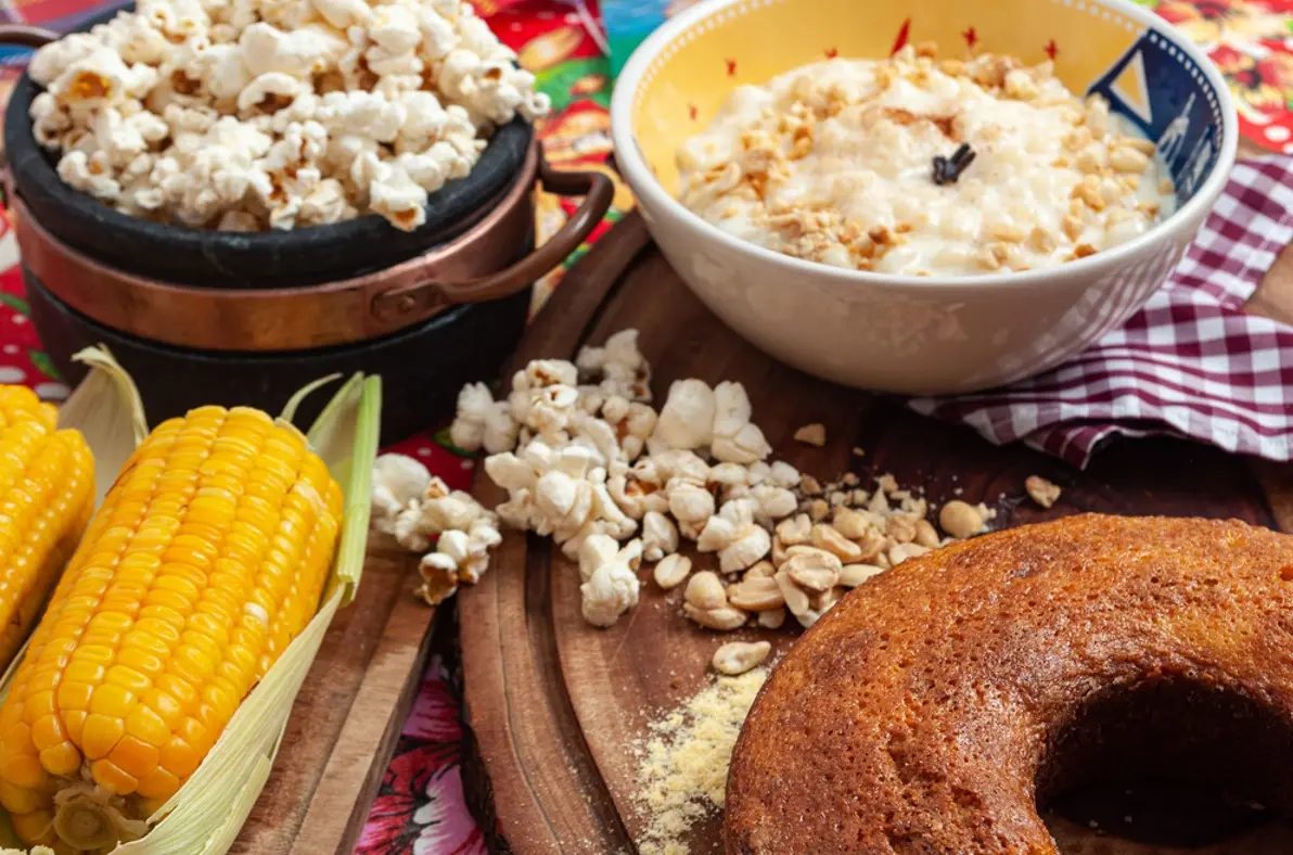 foto de mesa com comidas típicas de São João como milho, pipoca bolo e mugunzá