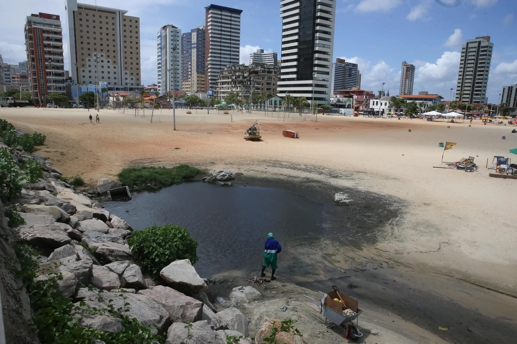 Homem limpando água escura na praia de iracema