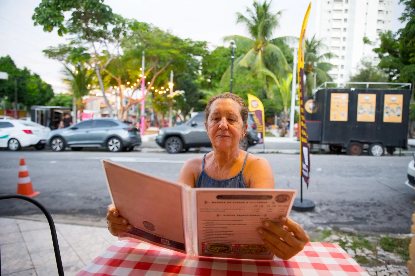 Na imagem, cliente com cardápio do Pizza na Praça, localizado no bairro de Fátima, em Fortaleza