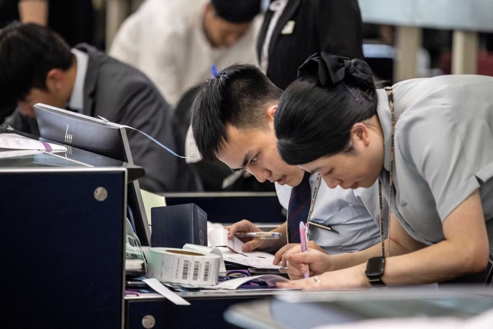 Comissários de um aeroporto em Hong Kong fazem o check-in manualmente