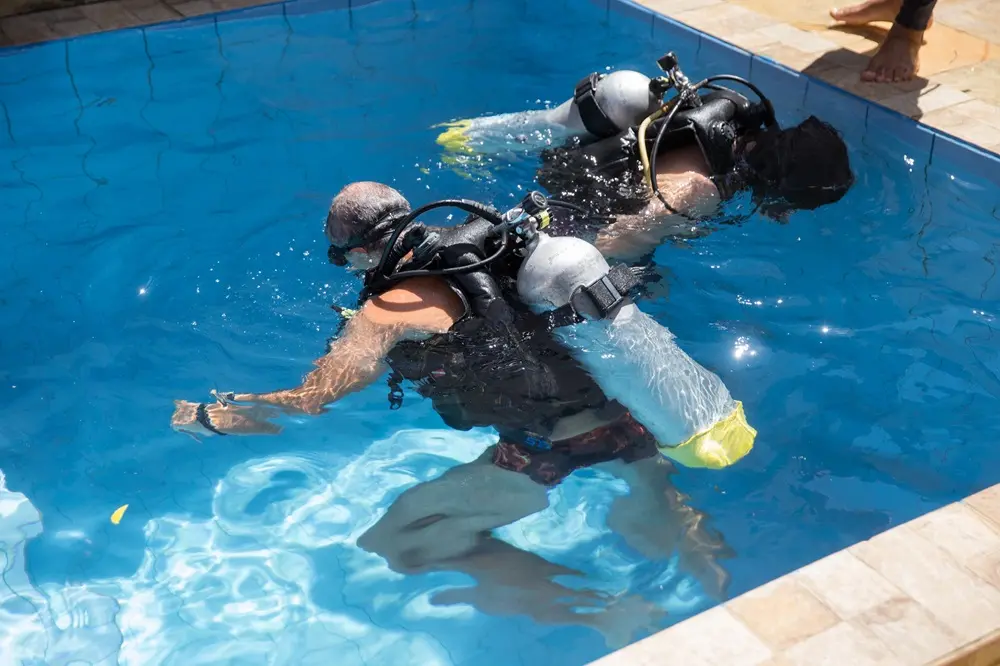 Na imagem, instrutor de mergulho em Fortaleza dá orientações a alunos na piscina da empresa
