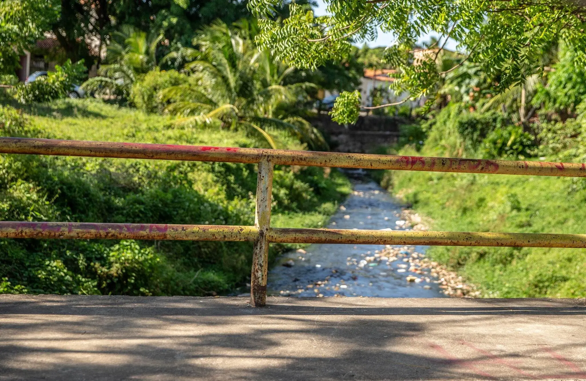 Vista de uma ponte sobre um rio, com uma grade simples