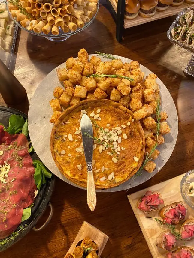 Quiche e dadinhos de tapioca em uma mesa de grazing table