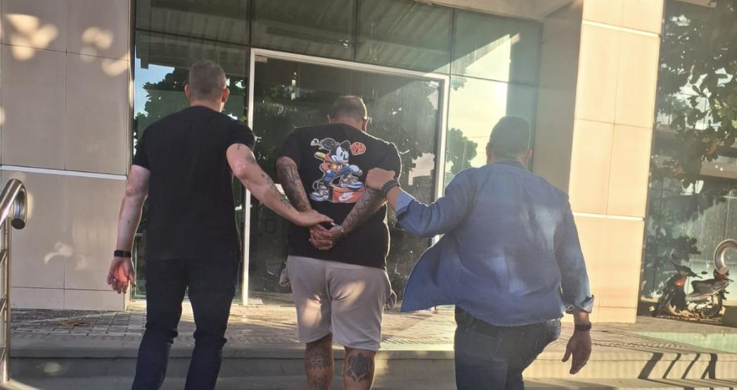 Foto de um homem identificado como Netão Marley sendo preso e levado a uma delegacia da Polícia Civil