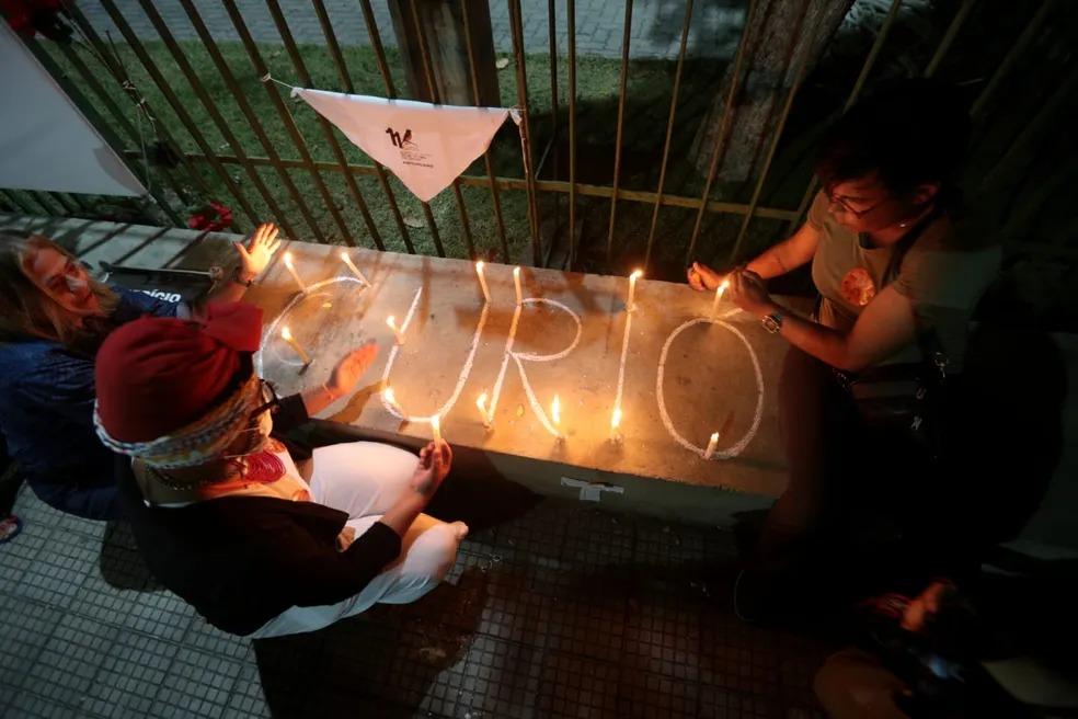 Foto mostra pessoas acendendo velas no aguardo do desfecho de um julgamento da Chacina do Curió, em Fortaleza