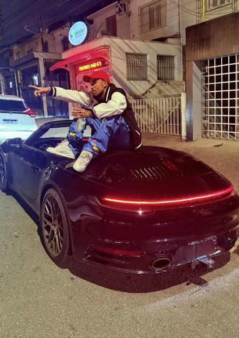 gato preto sentado em cima de porsche preto