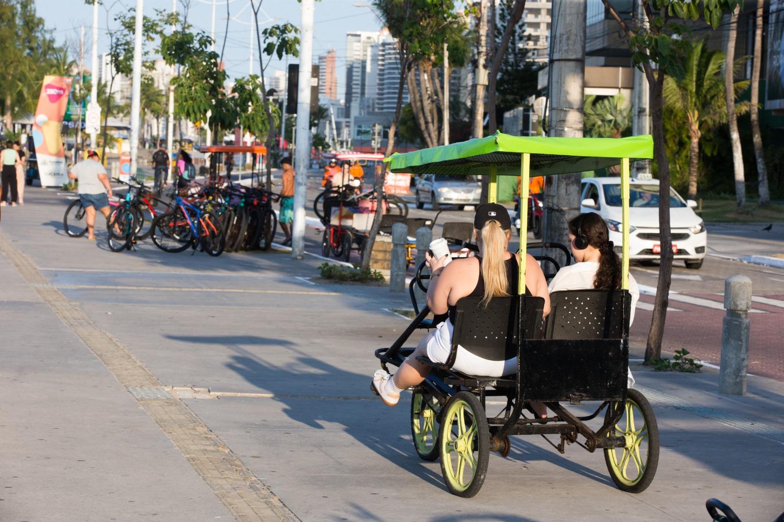 Mulheres andando em triciclo no passeio da beira-mar de Fortaleza