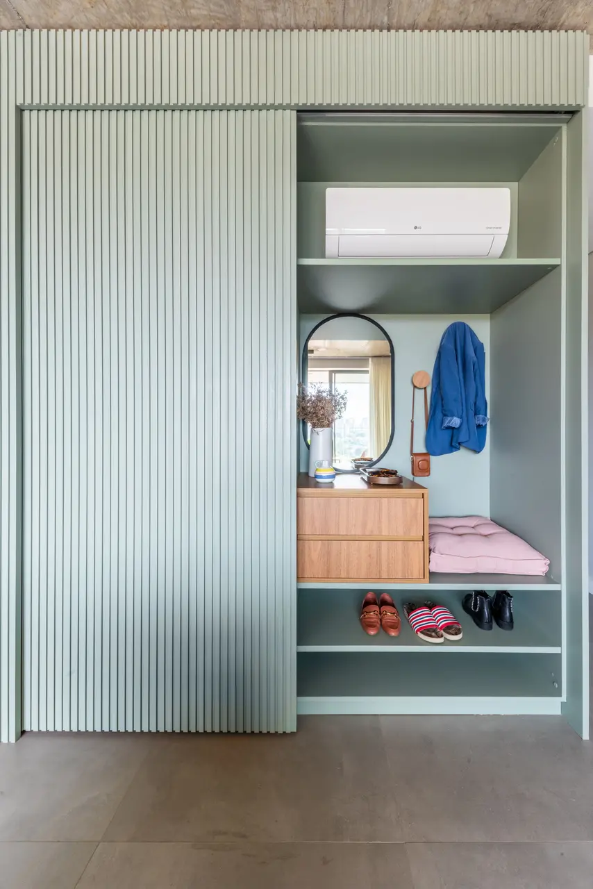 No hall de entrada, a marcenaria funciona como uma sapateira. Quando a porta desliza para um lado, abre-se o cantinho para os calçados