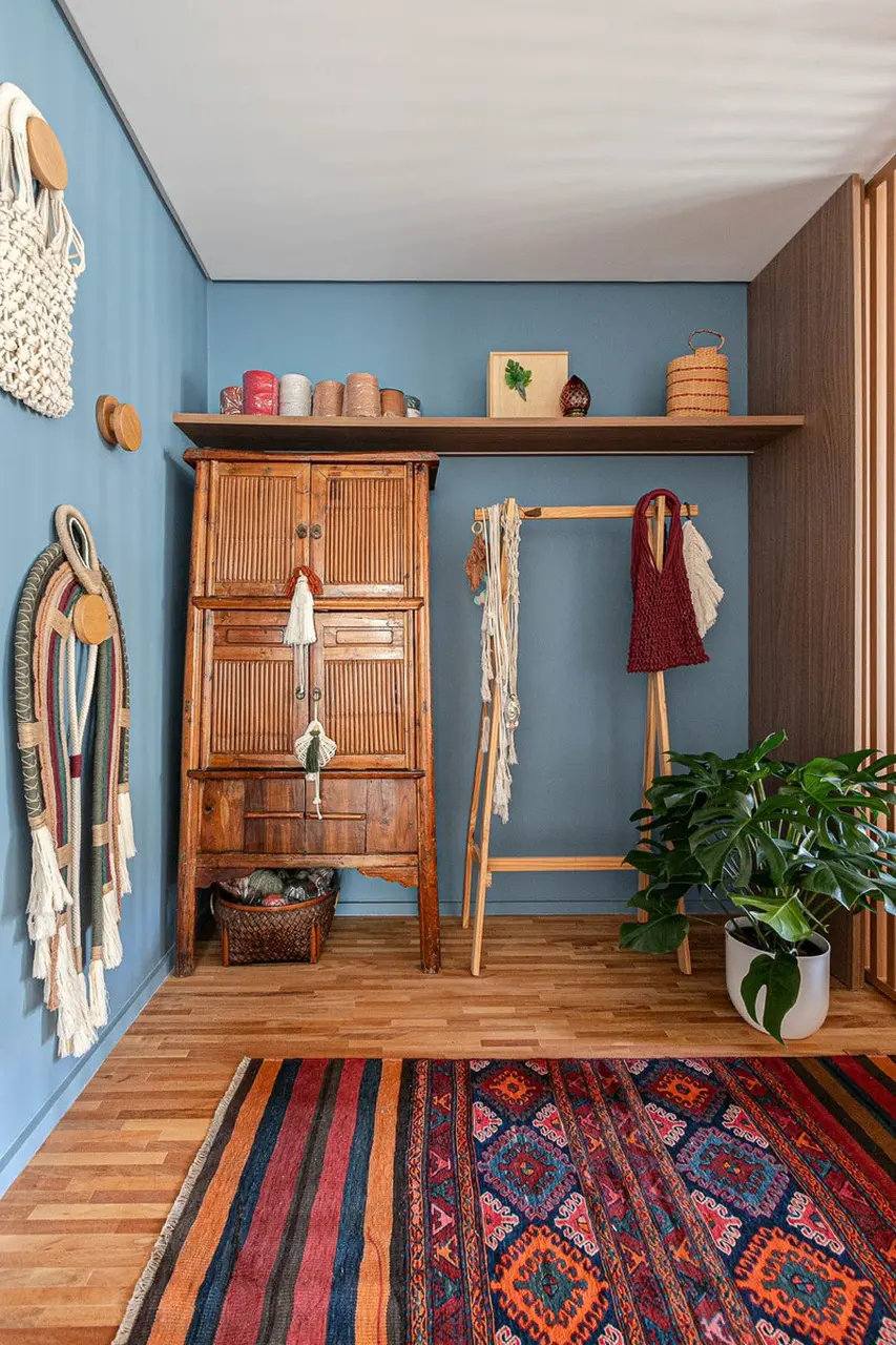 Com a cor azul, o hall de entrada torna marcante a a entrada do apê. Com espaço disponível, foi possível colocar um armário, cabideiro, tapete, prateleira e adornos decorativos