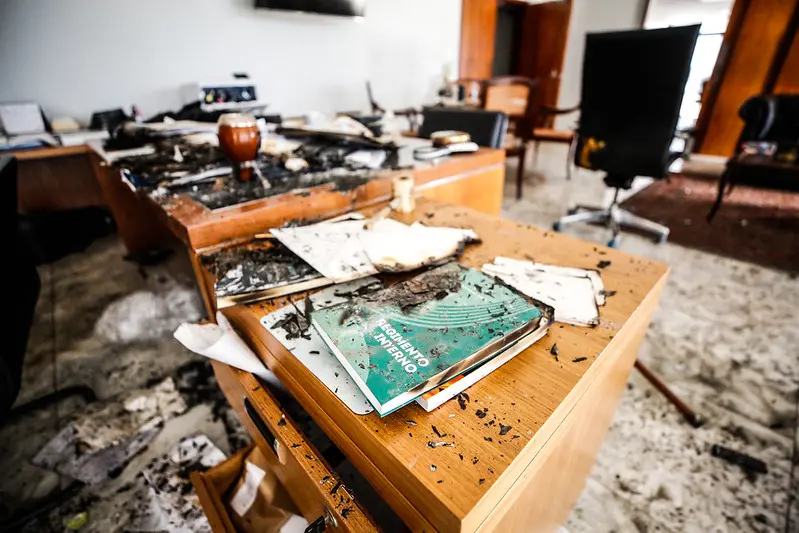 Gabinete de ministro do STF vandalizado, com cinzas sobre a mesa