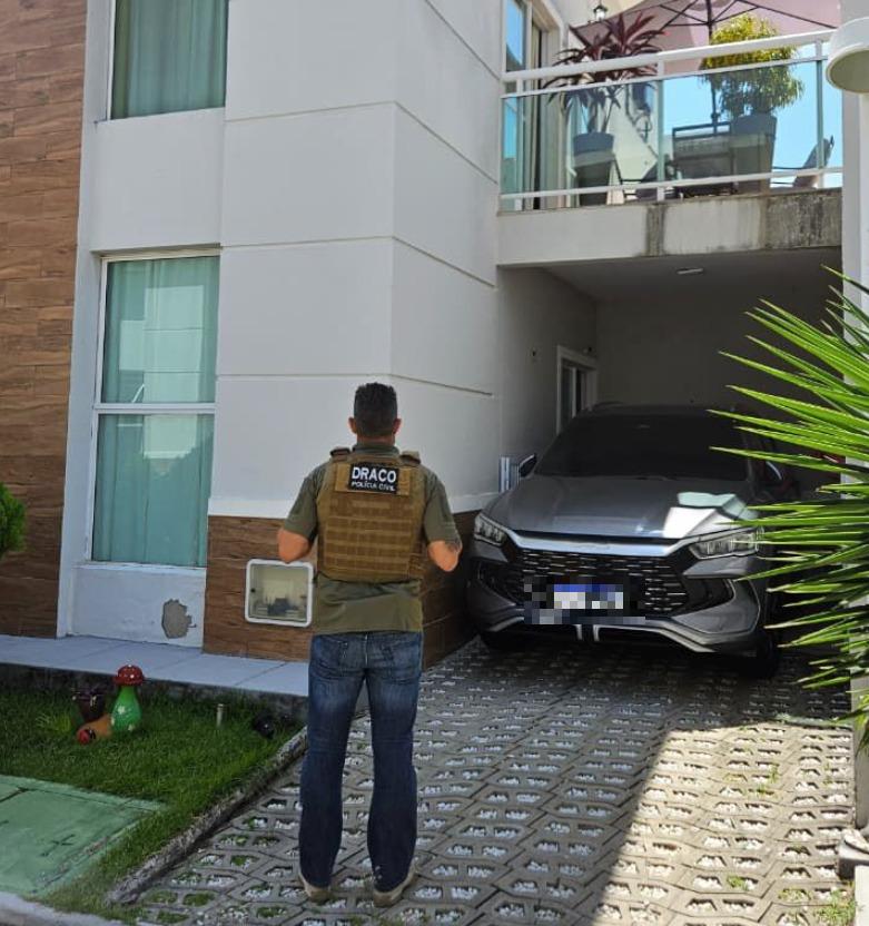 A foto mostra um policial civil em cumprimento de mandado de busca e apreensão em um condomínio de luxo no Ceará. Um veículo BYD de cor cinza foi apreendido
