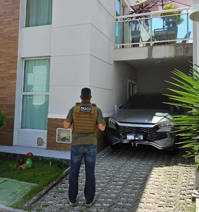 A foto mostra um policial civil em cumprimento de mandado de busca e apreensão em um condomínio de luxo no Ceará. Um veículo BYD de cor cinza foi apreendido