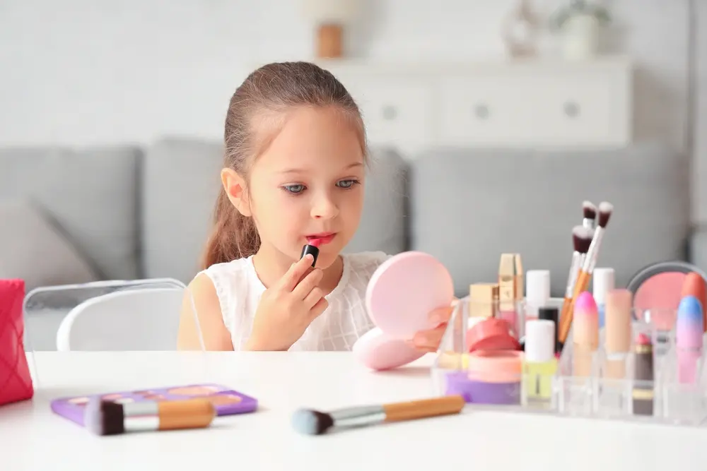foto de criança em frente ao espelho aplicando maquiagem no rosto