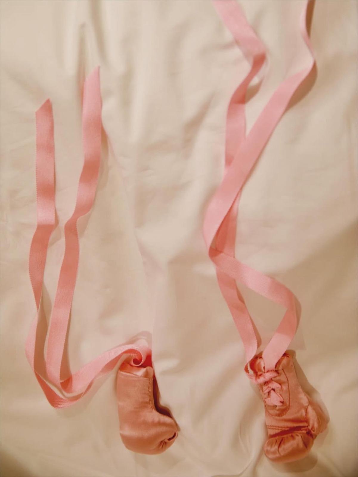 Luvinhas de bebê na cor rosa dispostas em uma cama