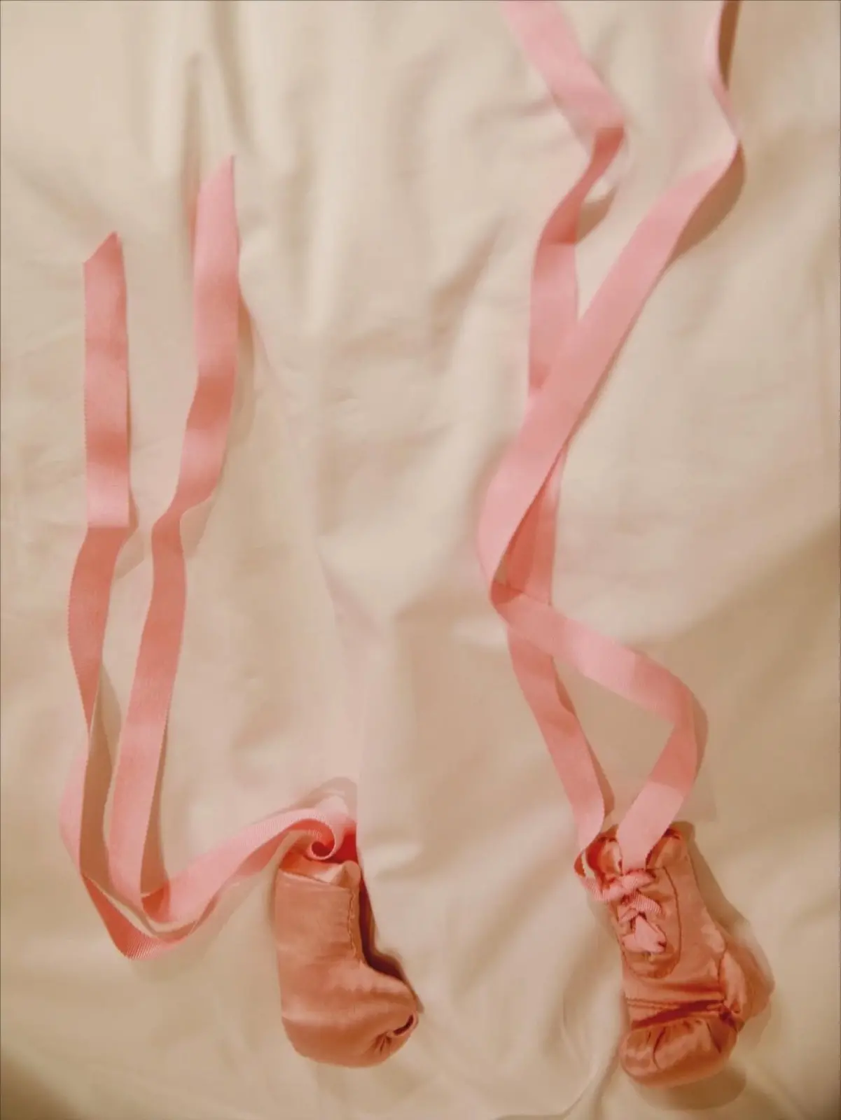 Luvinhas de bebê na cor rosa dispostas em uma cama