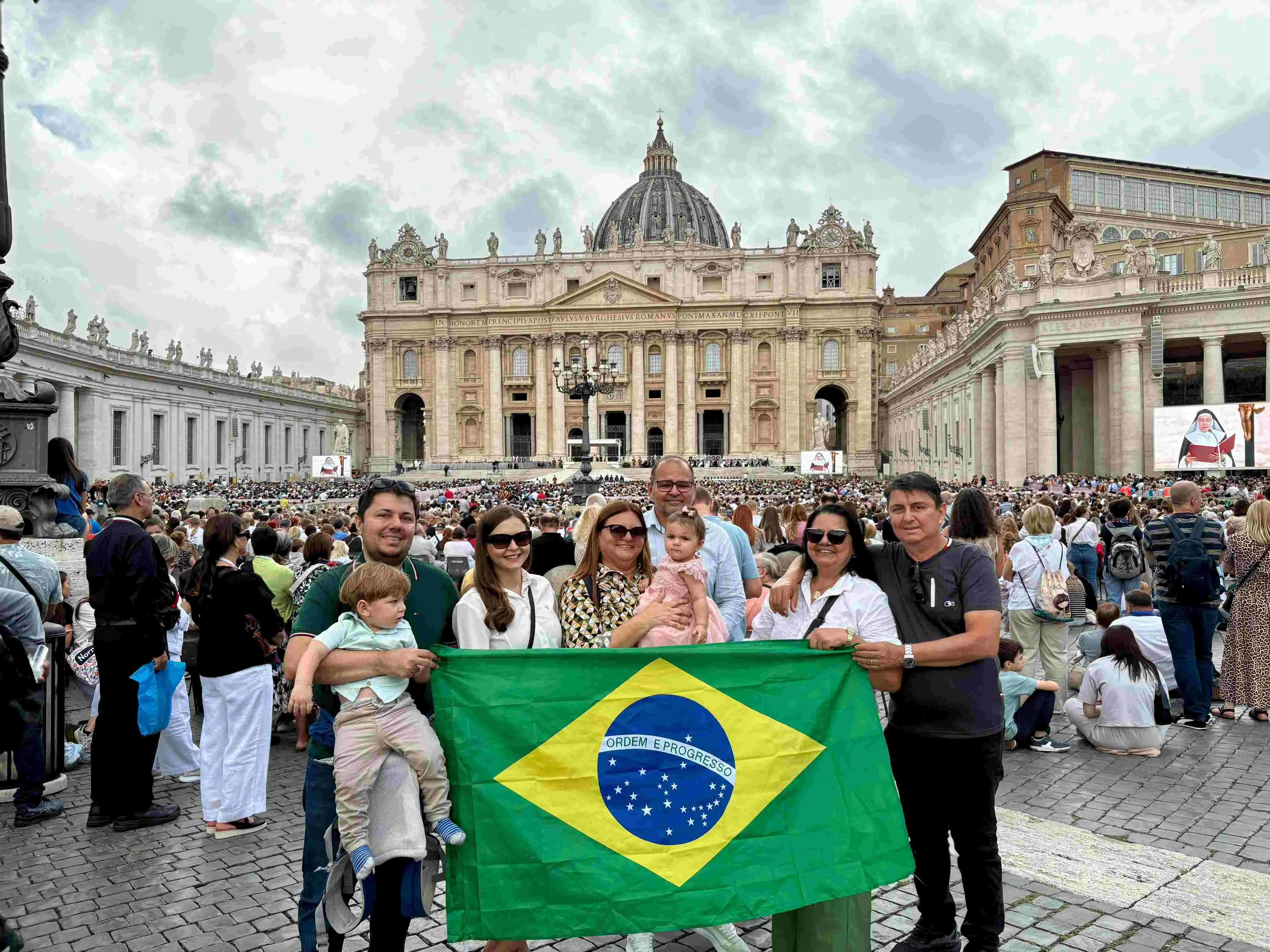 Na foto está um grupo de pessoas reunidas segurando a bandeira do Brasil