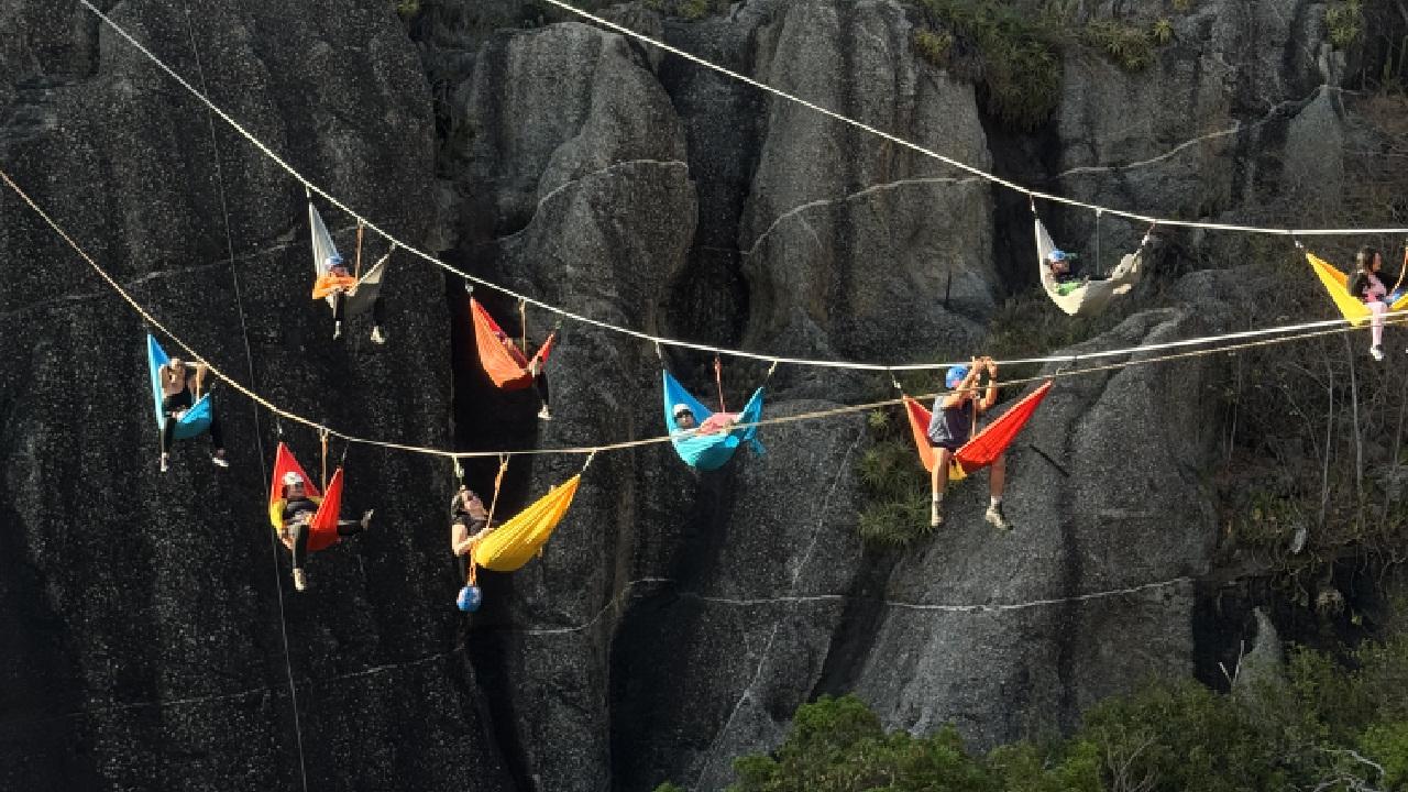 Grupo de pessoas deitadas em redes coloridas no alto da Ponte da Barra