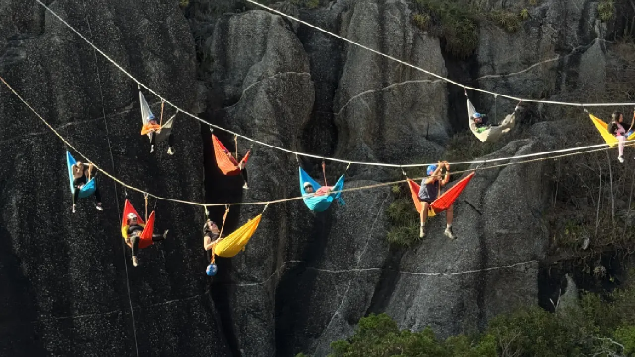 Grupo de pessoas deitadas em redes coloridas no alto da Ponte da Barra