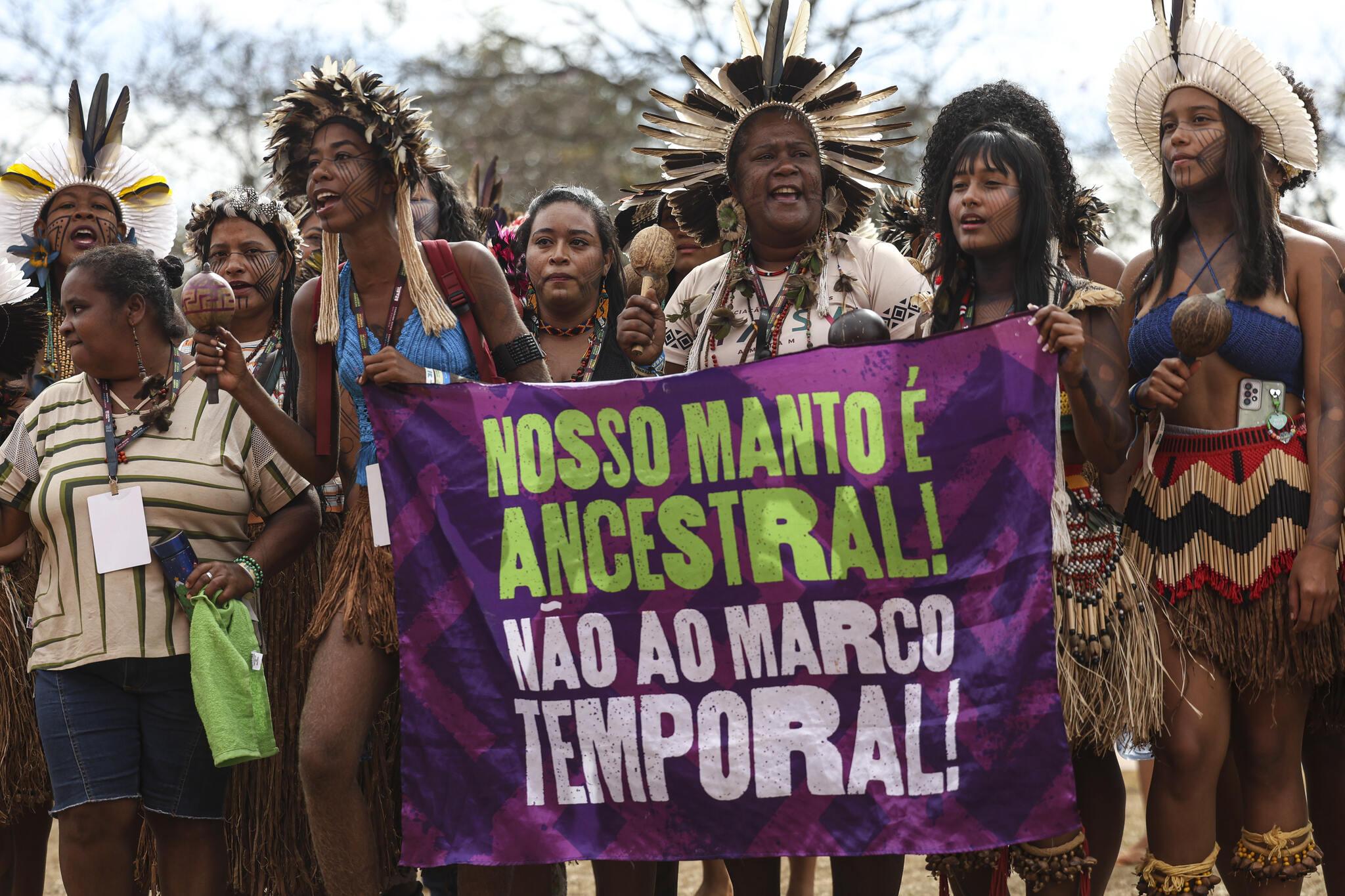 Mulheres indígenas na  1ª Conferência Nacional das Mulheres Indígenas, com cartaz em protesto contra o Marco Temporal