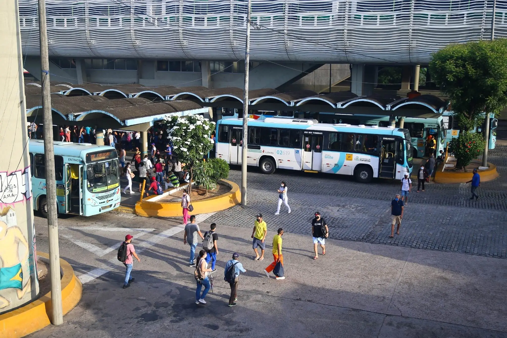 Vista aérea de terminal de ônibus de Fortaleza, com veículos parados e passageiros caminhando.
