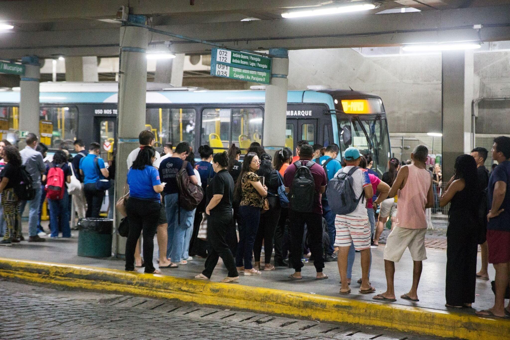 Passageiros em terminal de ônibus esperando o veículo.