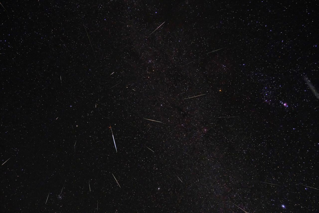 Céu noturno com traços cintilantes de uma chuva de meteoros.