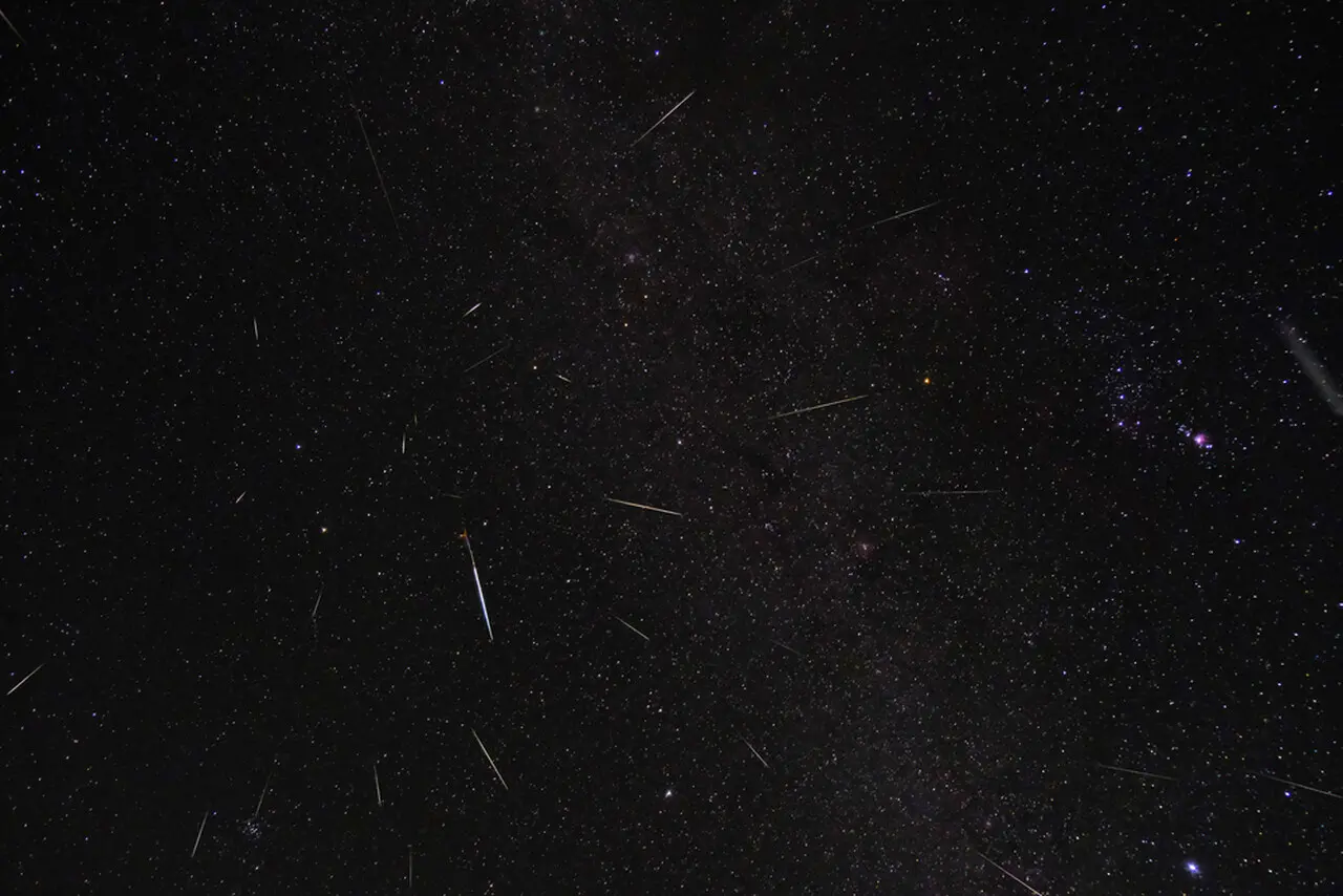 Céu noturno com traços cintilantes de uma chuva de meteoros.