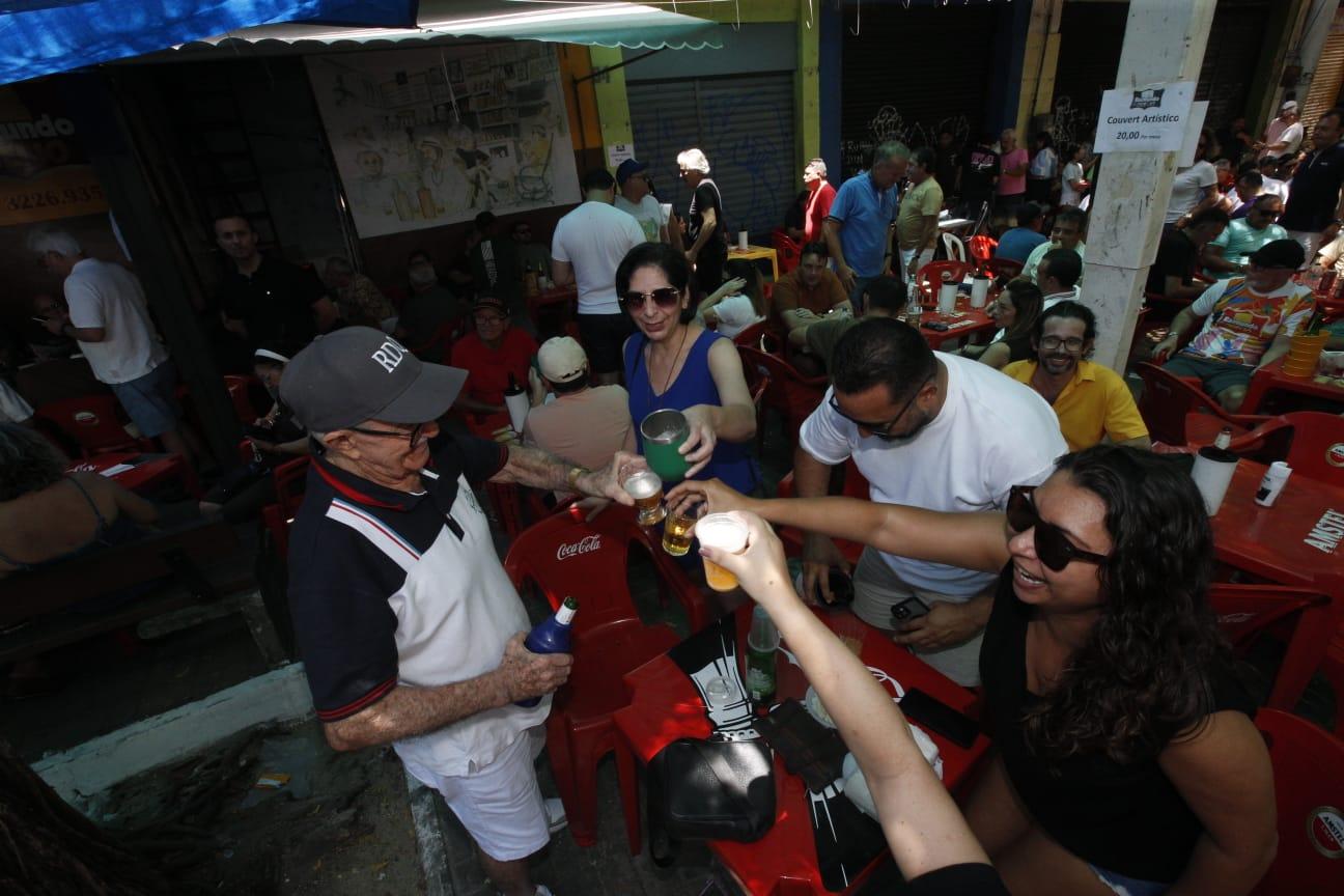 Foto de Raimundo do Queijo brindando com pessoas em mesa de bar.