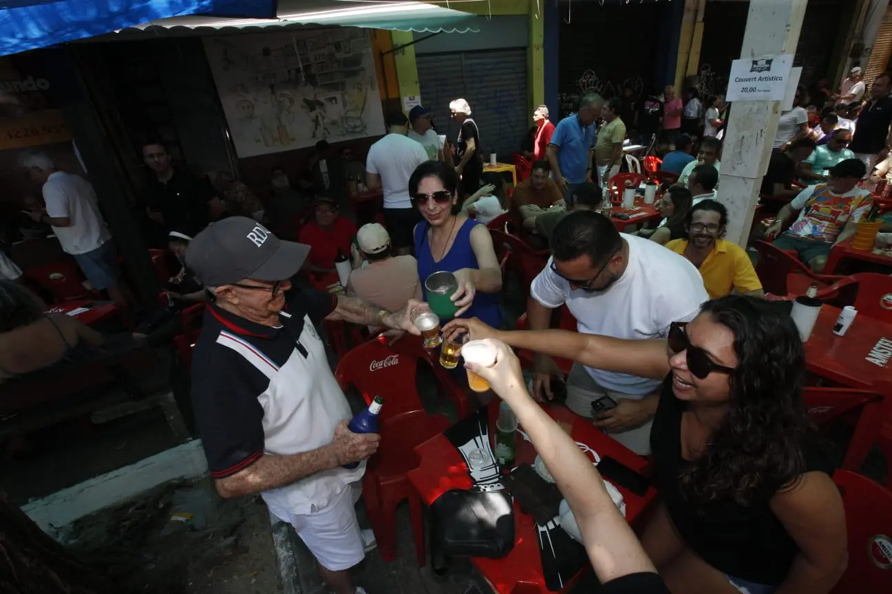 Foto de Raimundo do Queijo brindando com pessoas em mesa de bar.
