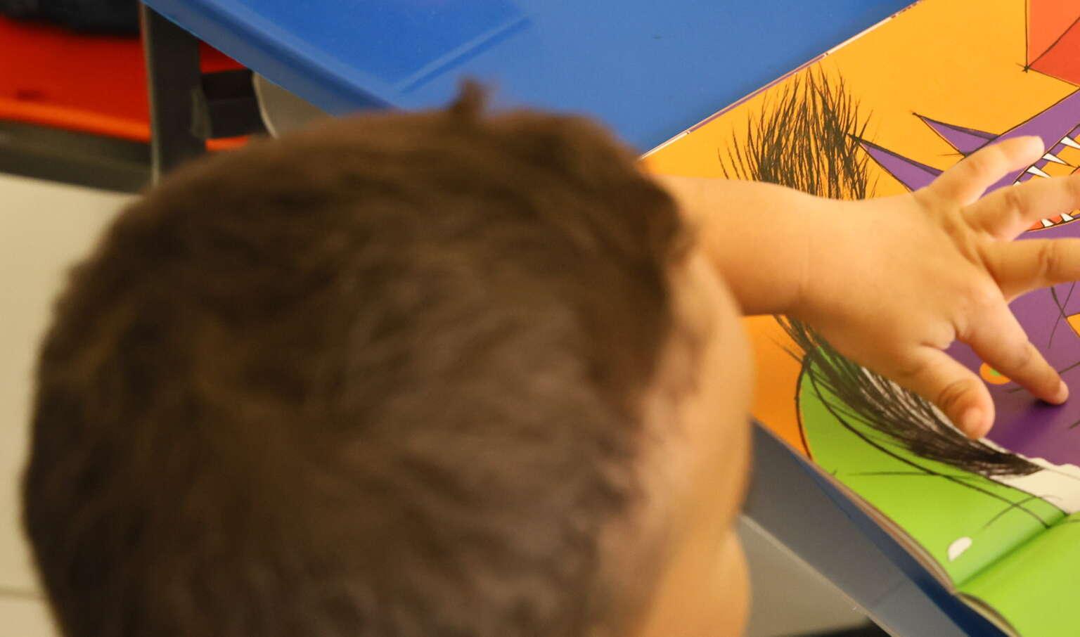 Uma criança manipula um desenho, pintando num papel.