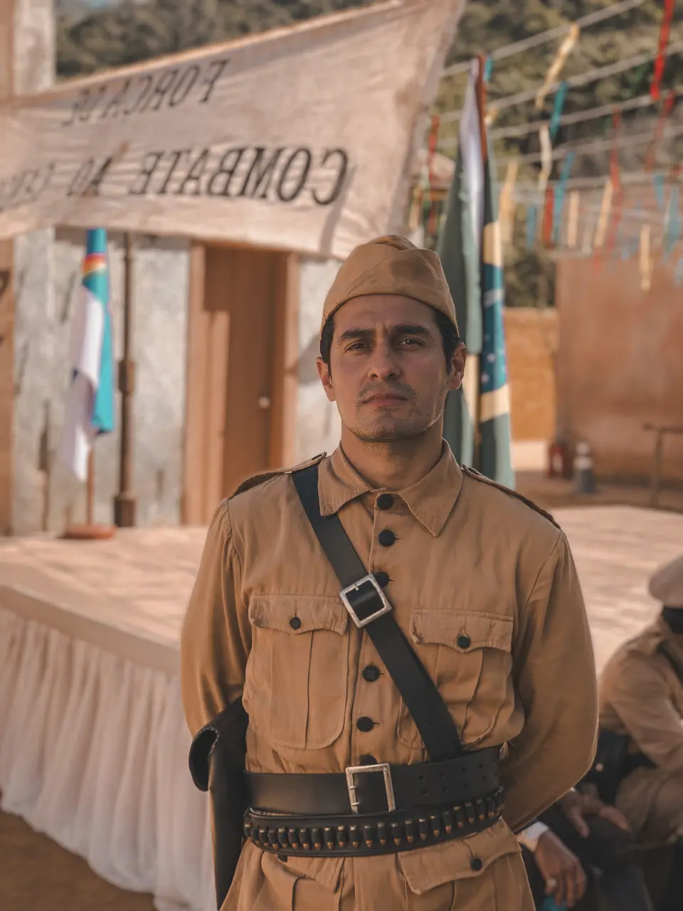 Imagem do ator cearense João Fontenele como o policial Arigó na novela 'Guerreiros do Sol', trajando uniforme bege.