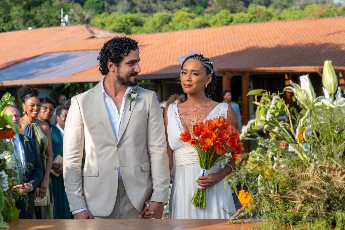 Raquel e Ivan subindo ao altar em Vale Tudo. Raquel segura um buquê de rosas laranjas.